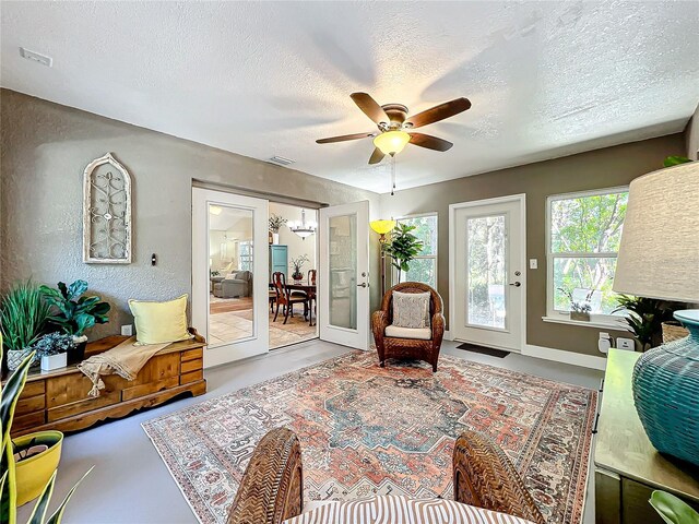 sitting room with ceiling fan, concrete floors, a textured ceiling, and french doors