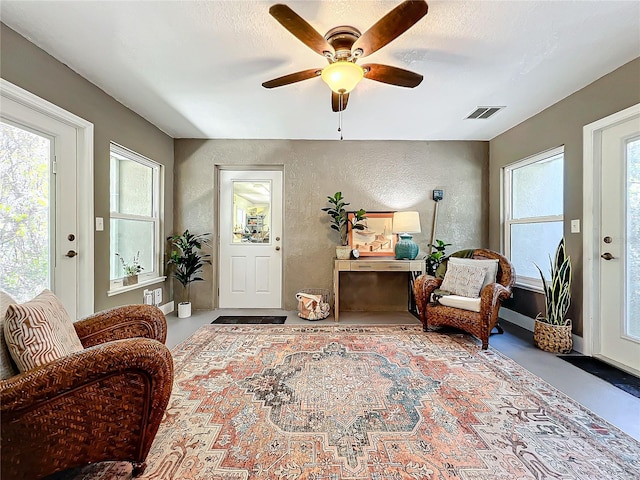 sitting room with concrete flooring, a textured ceiling, and ceiling fan