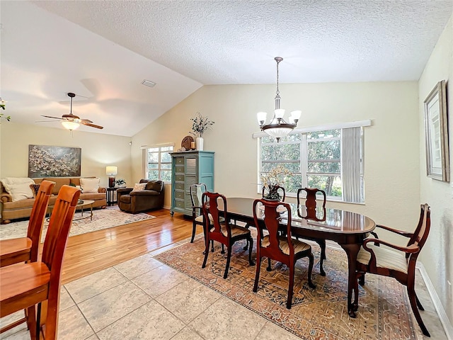 dining space with ceiling fan with notable chandelier, light hardwood / wood-style floors, lofted ceiling, and a textured ceiling