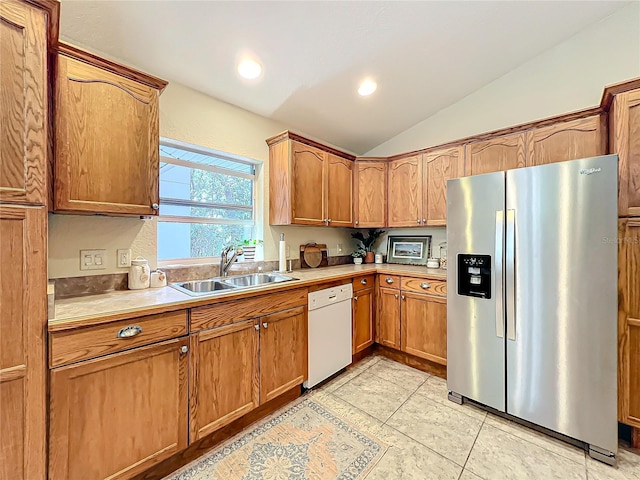 kitchen with dishwasher, lofted ceiling, sink, stainless steel fridge, and light tile patterned flooring