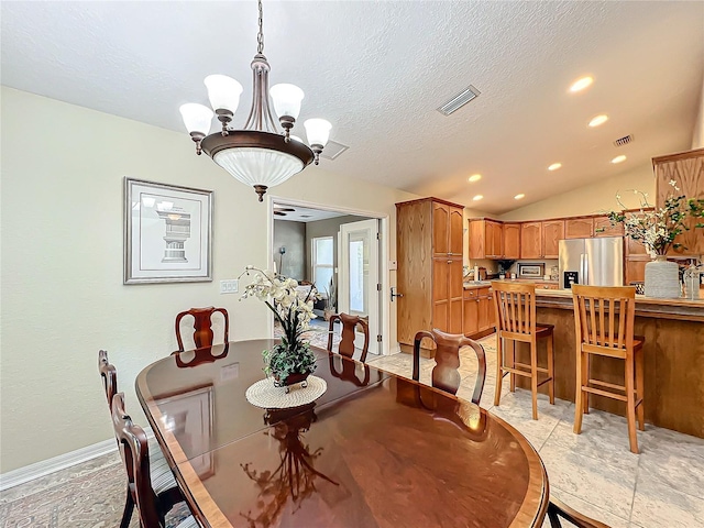 dining area featuring a textured ceiling, lofted ceiling, and an inviting chandelier