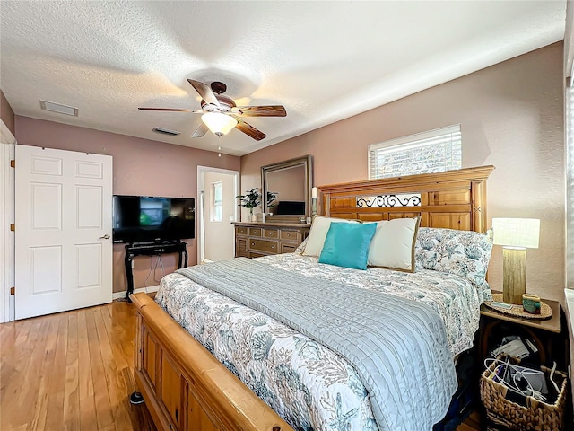 bedroom featuring ceiling fan, light wood-type flooring, and a textured ceiling