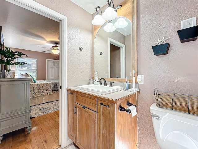 bathroom with ceiling fan, a textured ceiling, toilet, vanity, and hardwood / wood-style flooring