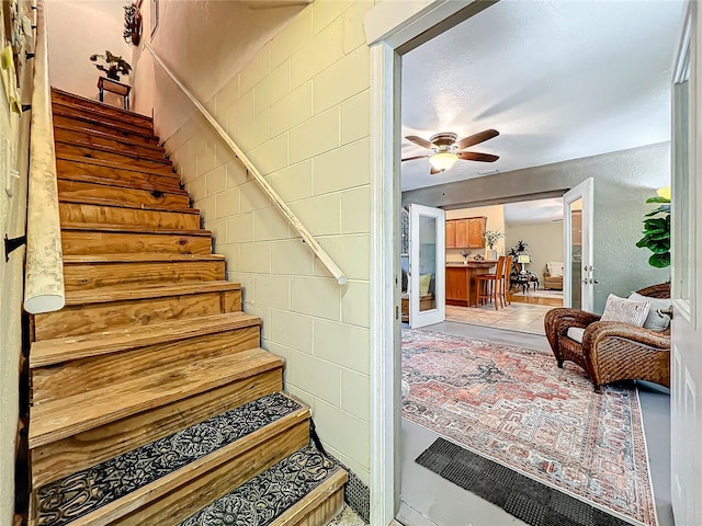 stairs with ceiling fan and french doors