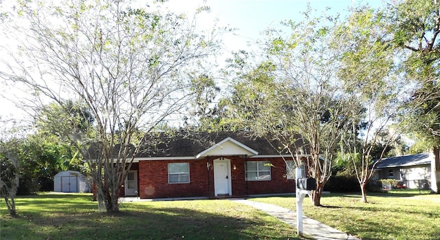 ranch-style home featuring a front yard and a storage unit