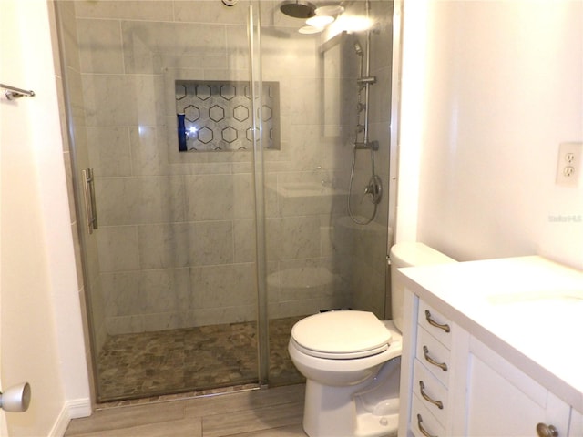 bathroom with a shower with door, vanity, wood-type flooring, and toilet