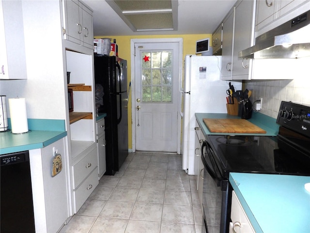 kitchen featuring backsplash, light tile patterned floors, and black appliances