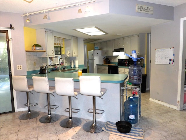 kitchen featuring white refrigerator, sink, light tile patterned floors, black / electric stove, and kitchen peninsula