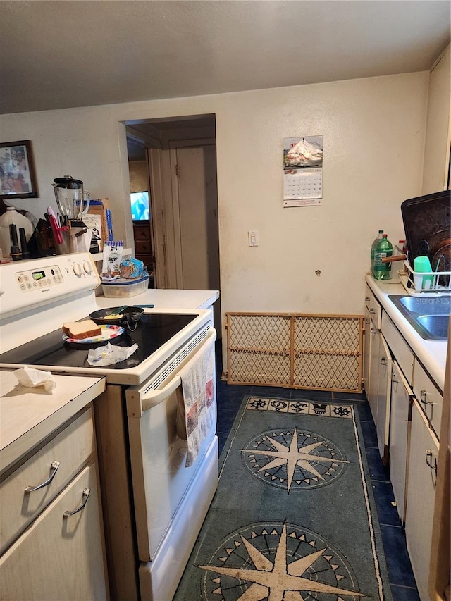 kitchen with sink, dark tile patterned flooring, and electric stove