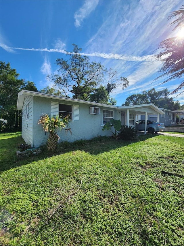 view of front of property with an AC wall unit and a front lawn