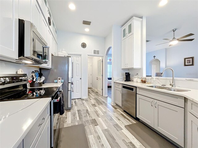 kitchen featuring stainless steel appliances, ceiling fan, sink, white cabinets, and light hardwood / wood-style floors