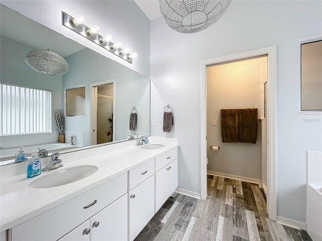 bathroom with plus walk in shower, wood-type flooring, vanity, and an inviting chandelier