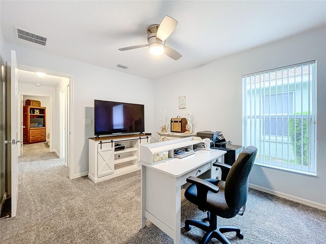 carpeted home office featuring ceiling fan