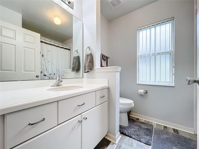 bathroom with vanity, wood-type flooring, a textured ceiling, and toilet