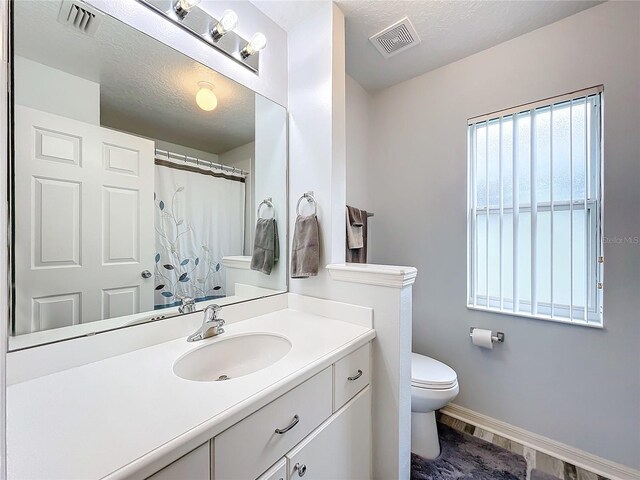 bathroom with vanity, a textured ceiling, hardwood / wood-style flooring, and toilet