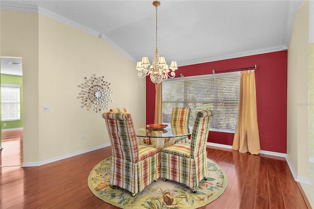 dining room with ornamental molding, a textured ceiling, a chandelier, hardwood / wood-style floors, and lofted ceiling