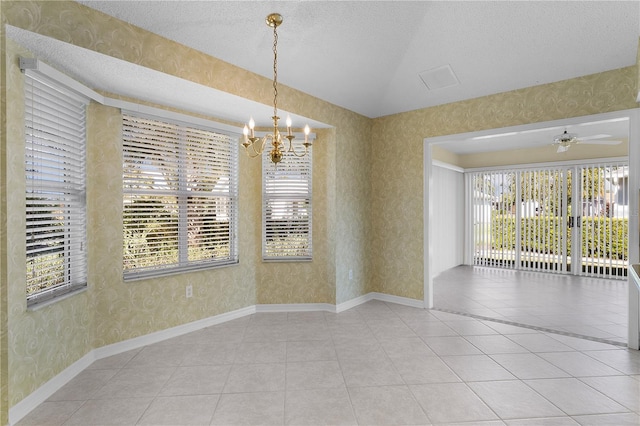 tiled empty room featuring lofted ceiling, ceiling fan with notable chandelier, and a textured ceiling