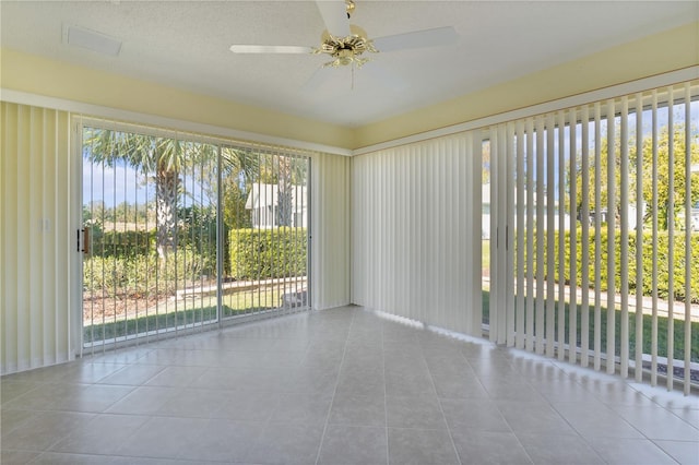 empty room with plenty of natural light, ceiling fan, and light tile patterned floors