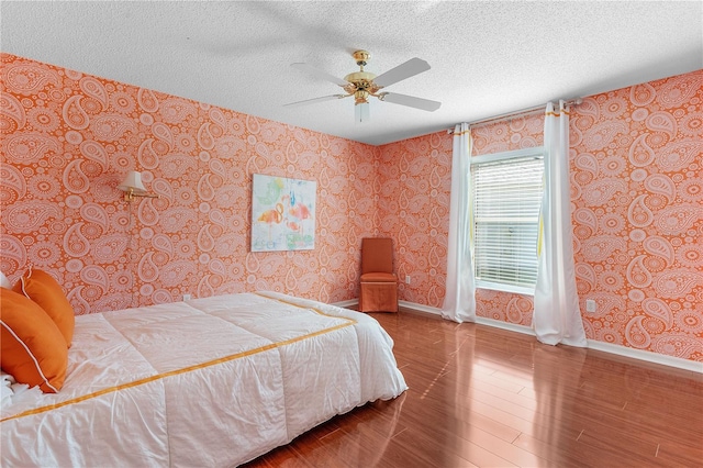 bedroom with wood-type flooring, a textured ceiling, and ceiling fan