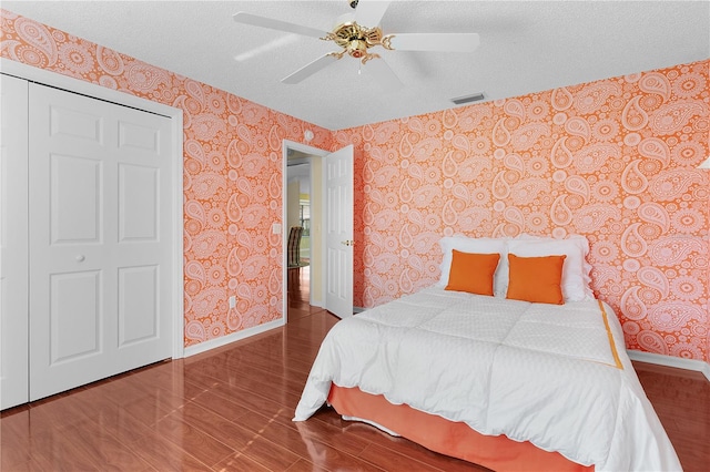 bedroom with ceiling fan, a closet, hardwood / wood-style floors, and a textured ceiling