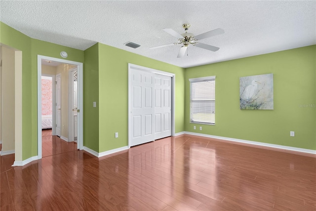 unfurnished bedroom with ceiling fan, dark hardwood / wood-style flooring, and a textured ceiling