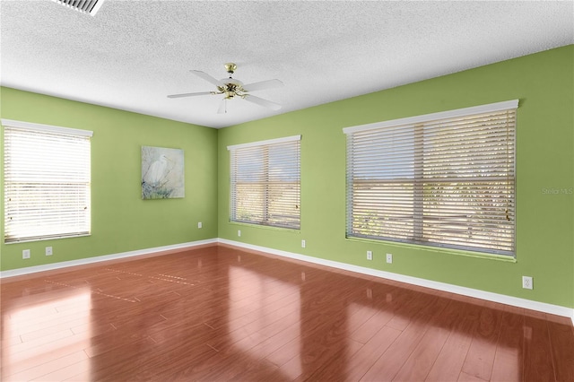 spare room featuring hardwood / wood-style floors, a healthy amount of sunlight, and a textured ceiling