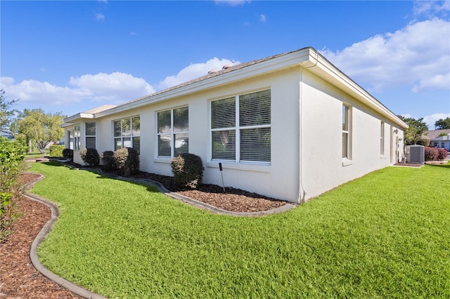 view of property exterior with central AC and a lawn