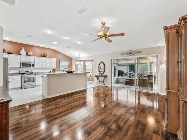 kitchen with white cabinetry, appliances with stainless steel finishes, decorative backsplash, hanging light fixtures, and ceiling fan with notable chandelier