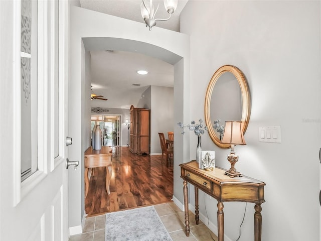 tiled entrance foyer featuring ceiling fan with notable chandelier