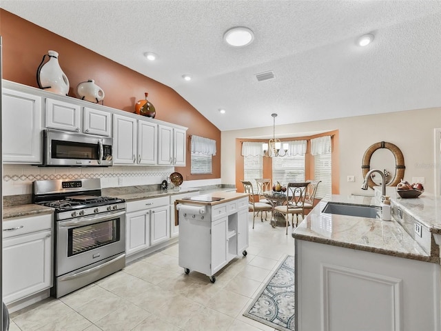 kitchen with hanging light fixtures, stainless steel appliances, white cabinets, and a kitchen island