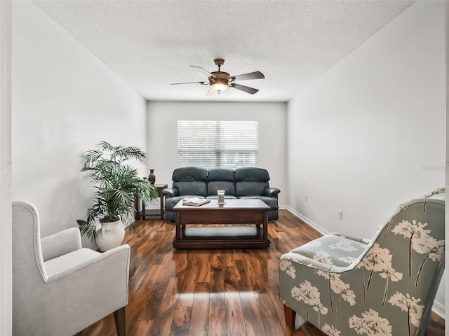 living room featuring ceiling fan, dark wood-type flooring, and a textured ceiling