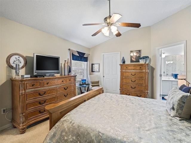 carpeted bedroom featuring ceiling fan, lofted ceiling, and ensuite bath