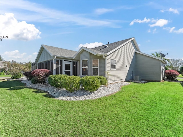 view of side of property featuring cooling unit, a sunroom, and a yard