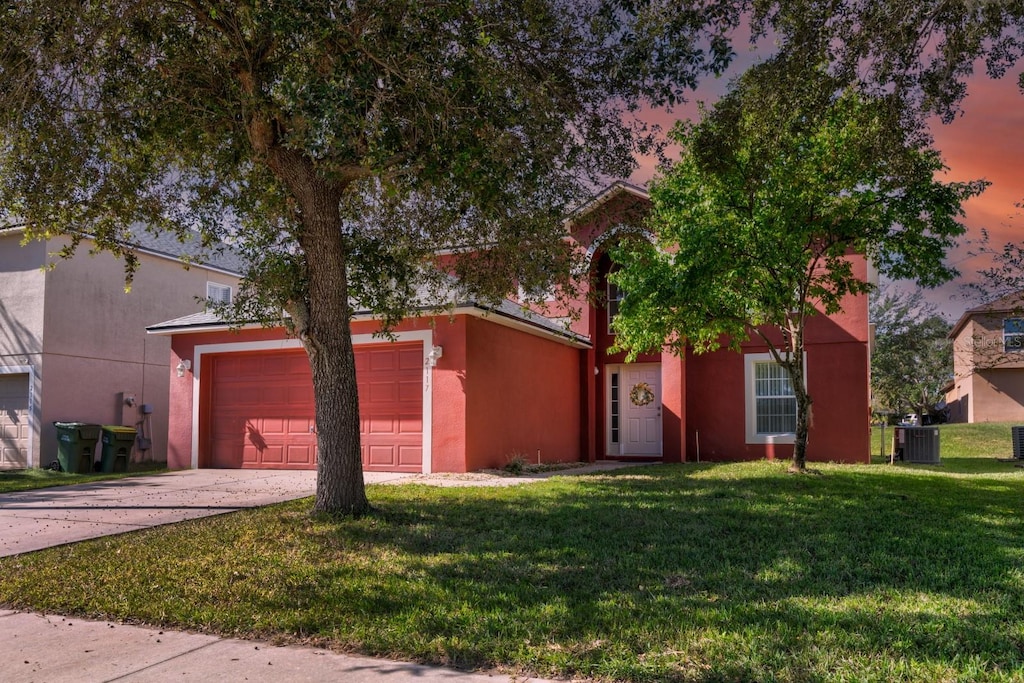 view of front of property featuring a yard and central AC