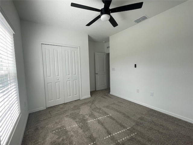 unfurnished bedroom featuring a closet, ceiling fan, and dark colored carpet