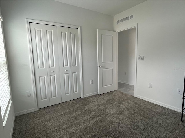 unfurnished bedroom with dark carpet and a closet