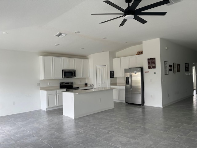 kitchen featuring appliances with stainless steel finishes, white cabinetry, lofted ceiling, sink, and a center island with sink