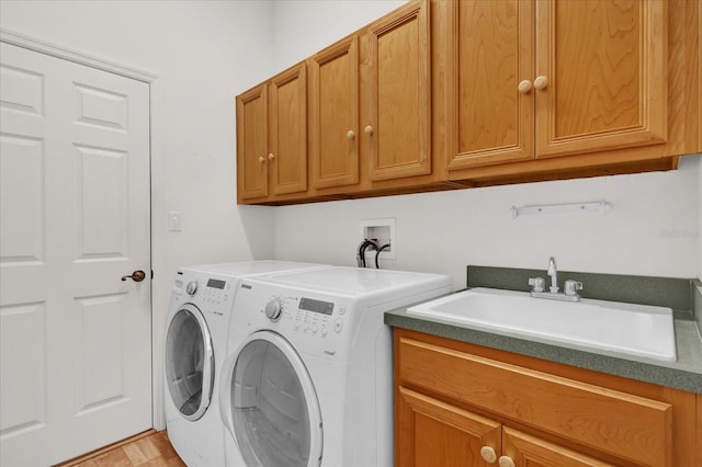 laundry area with cabinets, light wood-type flooring, washing machine and dryer, and sink