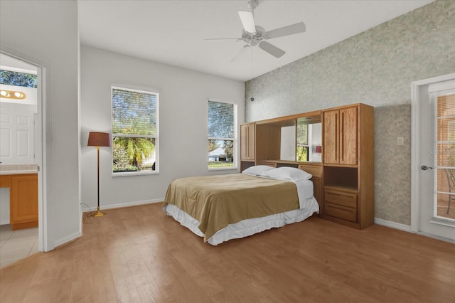 bedroom with multiple windows, connected bathroom, light hardwood / wood-style flooring, and ceiling fan