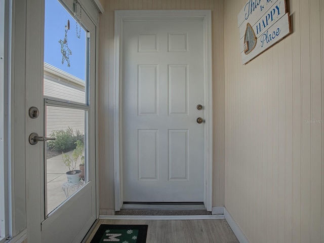 doorway to outside with plenty of natural light, wooden walls, and light hardwood / wood-style flooring