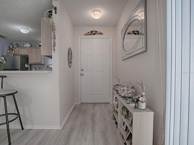 entryway featuring a textured ceiling and light hardwood / wood-style flooring