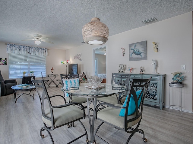 dining room featuring ceiling fan, light hardwood / wood-style flooring, and a textured ceiling