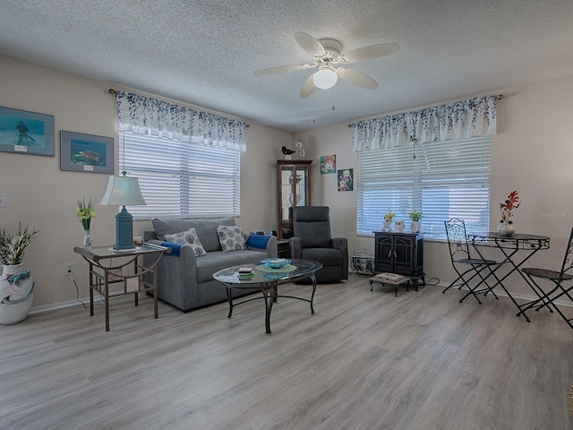 living room featuring ceiling fan, a textured ceiling, and light hardwood / wood-style flooring