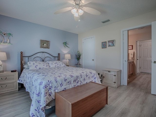 bedroom featuring ceiling fan, light hardwood / wood-style flooring, and a textured ceiling