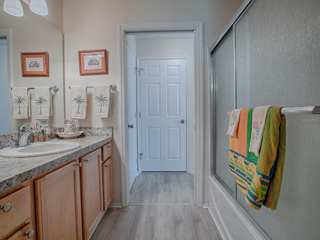 bathroom featuring enclosed tub / shower combo, vanity, and wood-type flooring