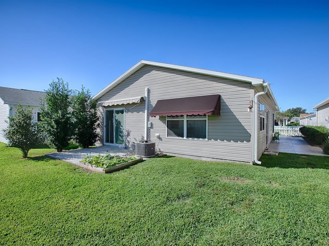 back of property featuring a lawn and central AC