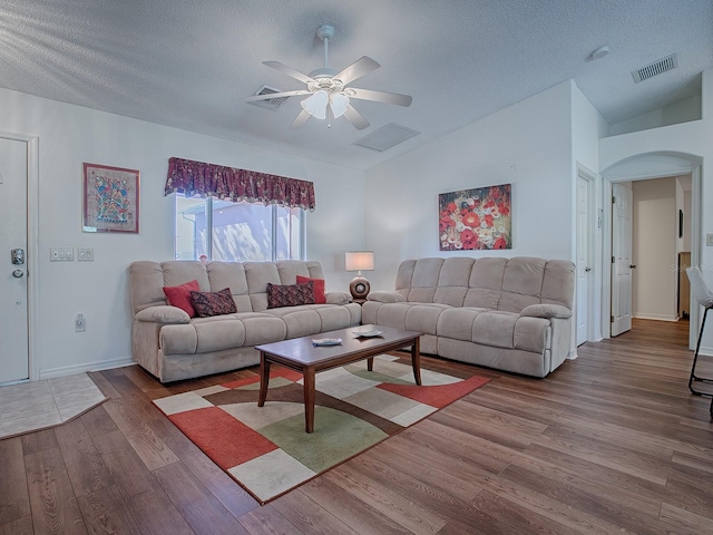 33236 Grand Cypress Way, Leesburg, FL 34748 - living room featuring lofted ceiling, wood finished floors, ceiling fan, arched walkways, and a textured ceiling