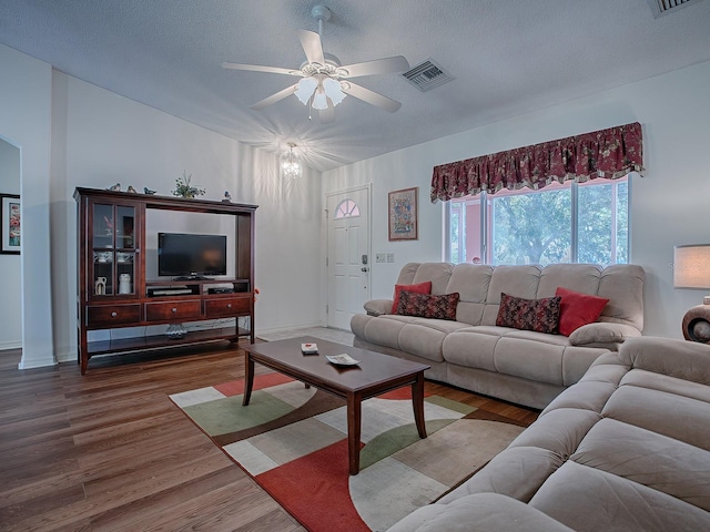 living room featuring wood-type flooring, a textured ceiling, and ceiling fan