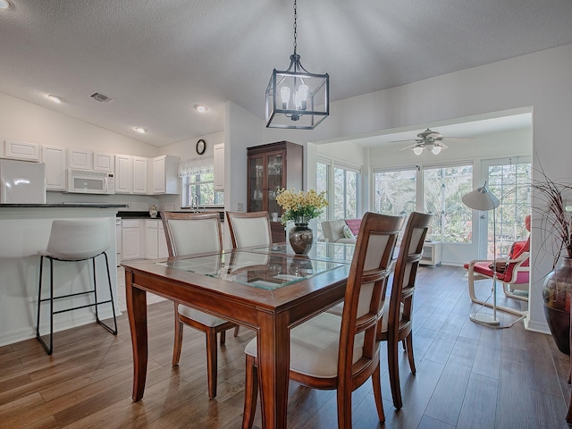 33236 Grand Cypress Way, Leesburg, FL 34748 - dining space with dark wood-type flooring, vaulted ceiling, ceiling fan, baseboards, and a textured ceiling