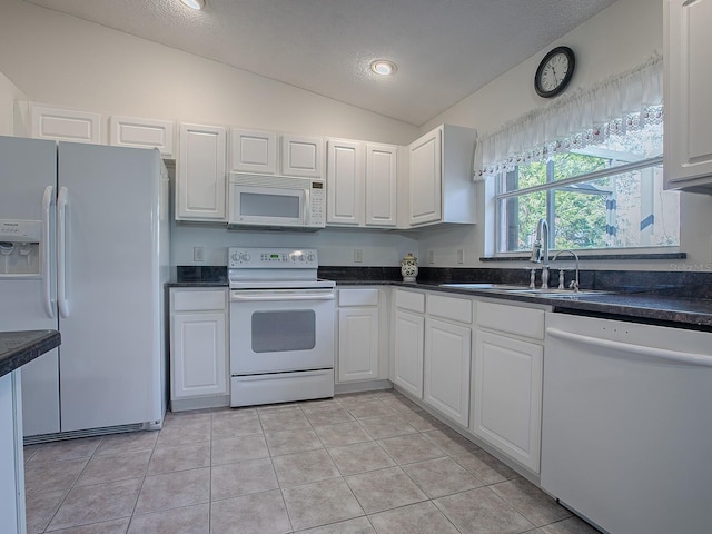 kitchen featuring lofted ceiling, white cabinetry, and white appliances